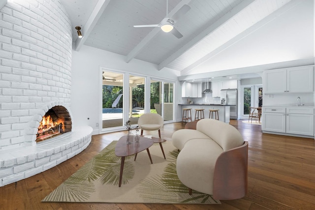 living room with beam ceiling, a fireplace, dark wood-type flooring, a ceiling fan, and high vaulted ceiling