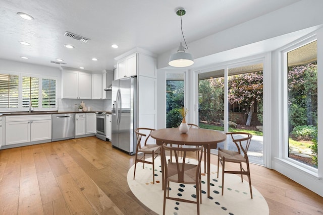 kitchen featuring recessed lighting, light wood-style flooring, white cabinetry, dark countertops, and appliances with stainless steel finishes