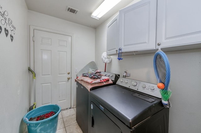clothes washing area featuring washer / dryer, visible vents, cabinet space, and light tile patterned flooring