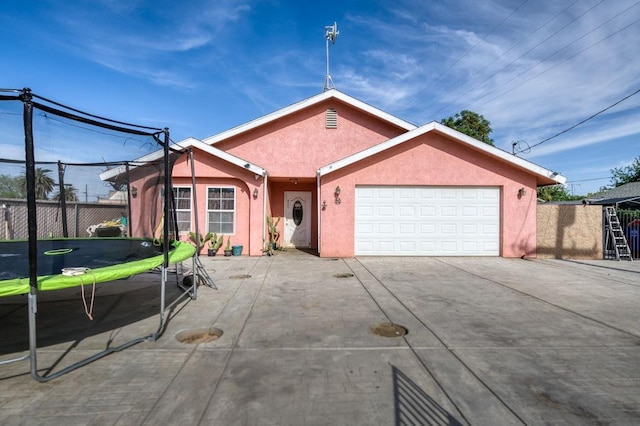 ranch-style house featuring fence, an attached garage, concrete driveway, and stucco siding