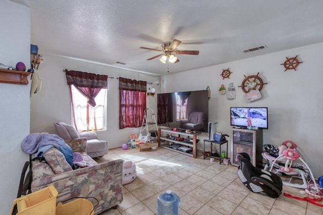 living room featuring a textured ceiling, visible vents, tile patterned flooring, and ceiling fan