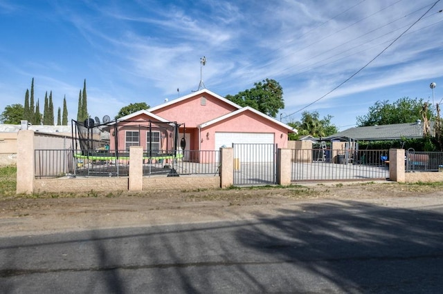 bungalow-style home with stucco siding, an attached garage, a fenced front yard, and driveway