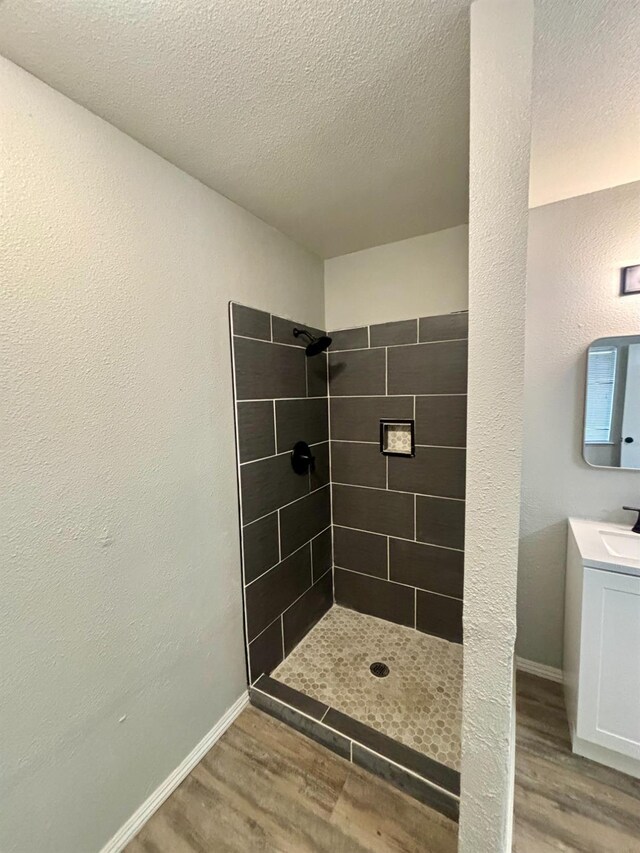 28813 Limestone Cir, Coarsegold, CA 93614 - full bath featuring wood finished floors, tiled shower, vanity, a textured ceiling, and baseboards