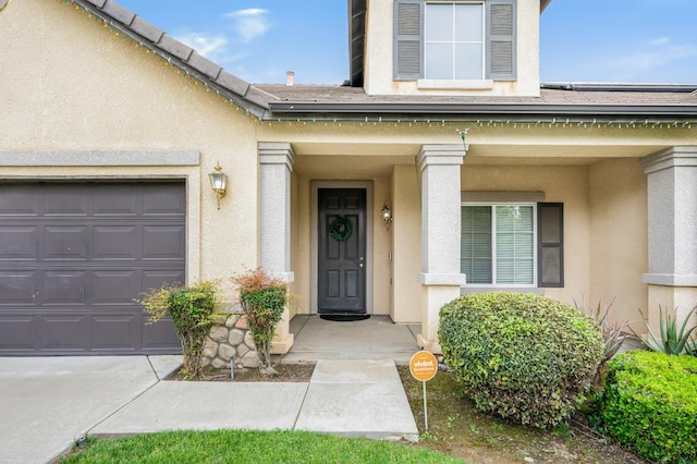 property entrance with a garage, roof with shingles, and stucco siding