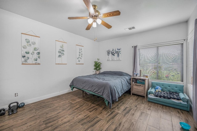bedroom with baseboards, a ceiling fan, wood finished floors, and visible vents