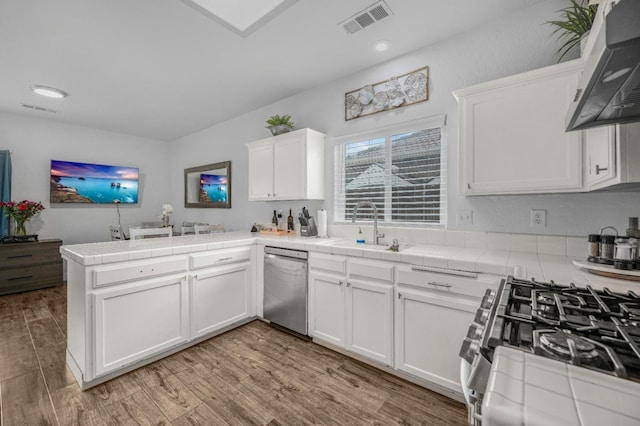 kitchen featuring tile counters, stainless steel appliances, visible vents, and a sink