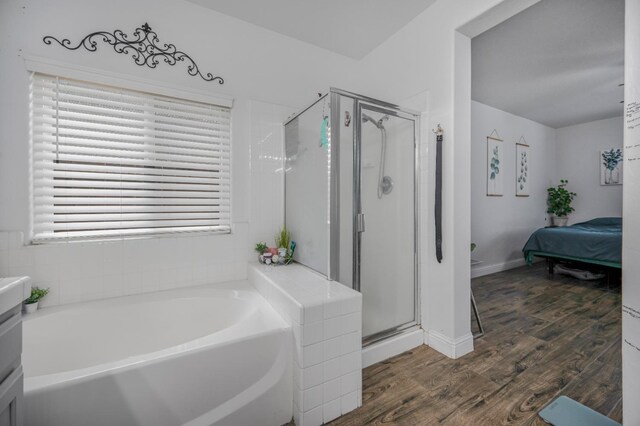 bathroom featuring a shower stall, a garden tub, a wealth of natural light, and wood finished floors