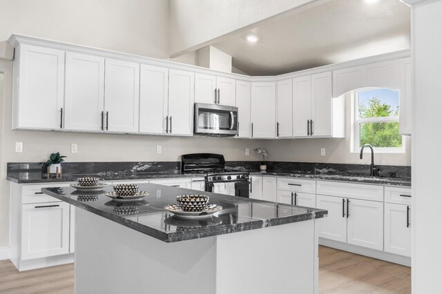 3659 Mono St, Fresno, CA 93702 - kitchen featuring stainless steel microwave, gas stove, white cabinets, light wood-style floors, and lofted ceiling