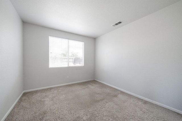 carpeted empty room featuring visible vents and baseboards