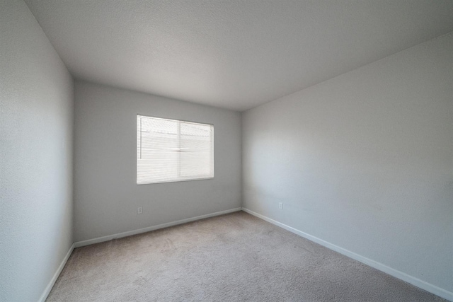 carpeted empty room with baseboards
