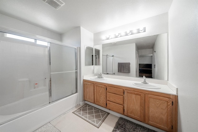bathroom with visible vents, bath / shower combo with glass door, a sink, and double vanity
