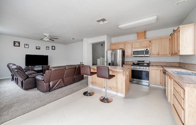 kitchen with light brown cabinetry, stainless steel appliances, visible vents, and a sink