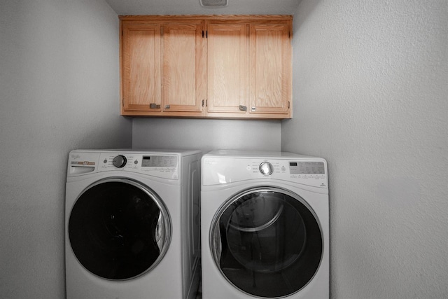 washroom with washer and clothes dryer and cabinet space