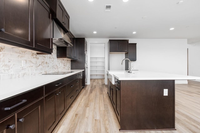 kitchen with light wood-style flooring, visible vents, decorative backsplash, black electric stovetop, and light countertops