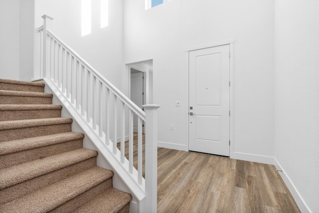 entrance foyer with a high ceiling, wood finished floors, stairs, and baseboards