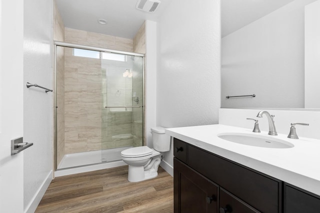 bathroom with toilet, visible vents, wood finished floors, a shower stall, and vanity