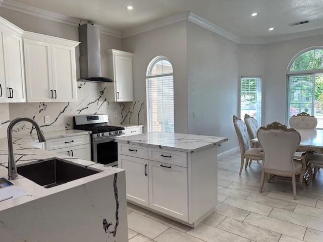 5357 E Burns, Fresno, CA 93725 - kitchen with wall chimney range hood, gas stove, light stone countertops, recessed lighting, and white cabinetry