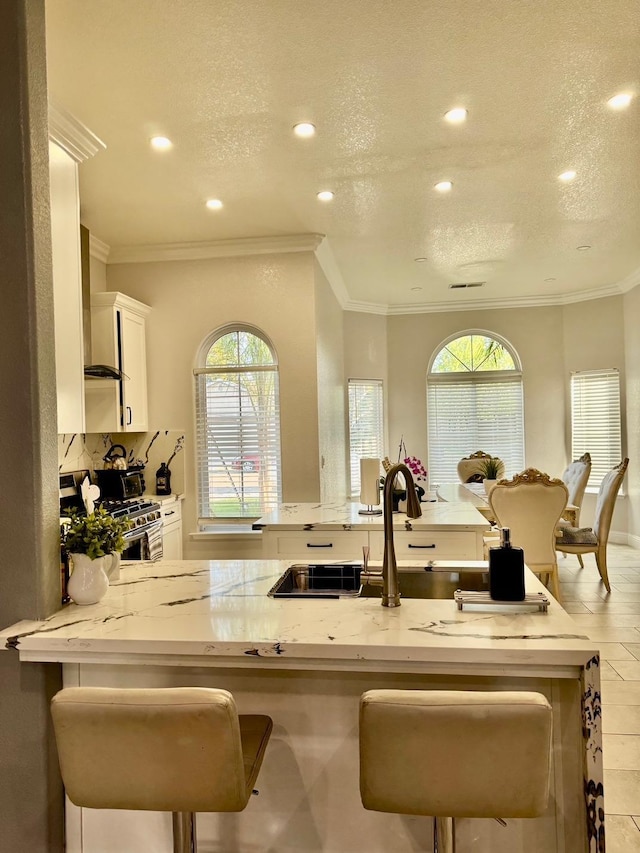 5357 E Burns, Fresno, CA 93725 - kitchen with recessed lighting, a kitchen bar, stainless steel range with gas stovetop, and white cabinetry
