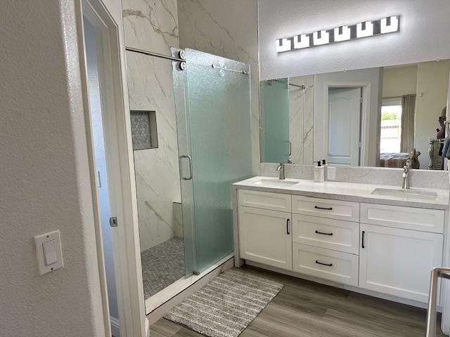 5357 E Burns, Fresno, CA 93725 - bathroom featuring a marble finish shower, wood finished floors, double vanity, and a textured wall