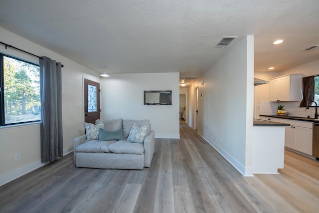 living area with light wood-style floors, visible vents, and recessed lighting