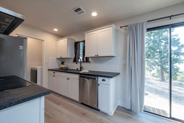 kitchen featuring dark countertops, a sink, a healthy amount of sunlight, appliances with stainless steel finishes, and visible vents