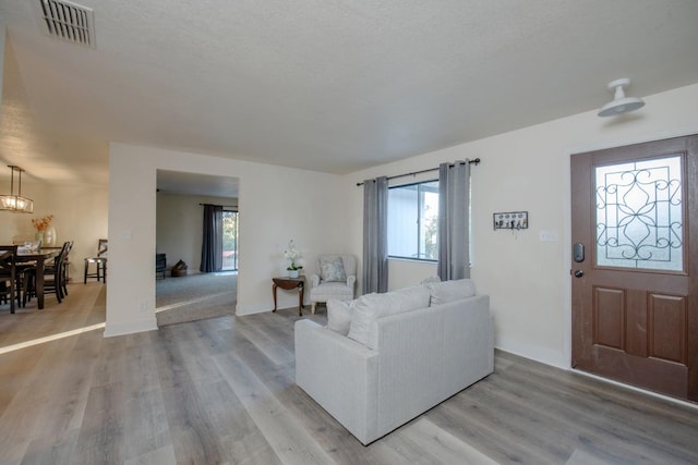 living area with a wealth of natural light, light wood finished floors, and visible vents
