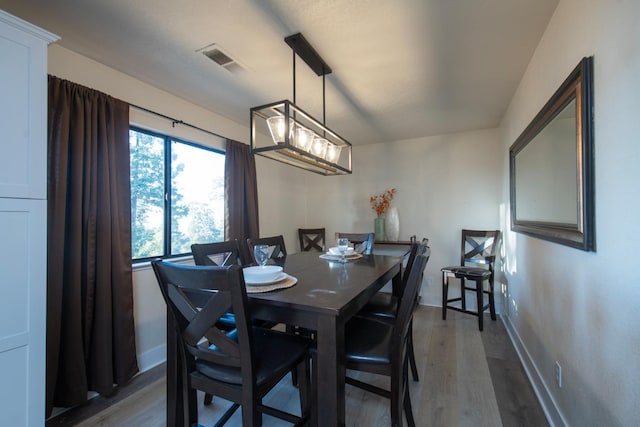 dining room featuring wood finished floors, visible vents, and baseboards