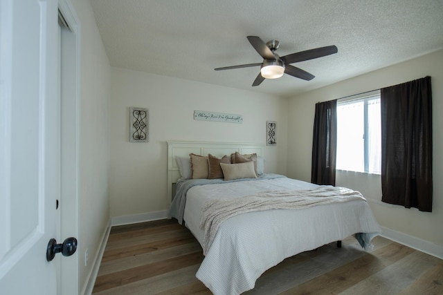 bedroom with baseboards, wood finished floors, a textured ceiling, and ceiling fan