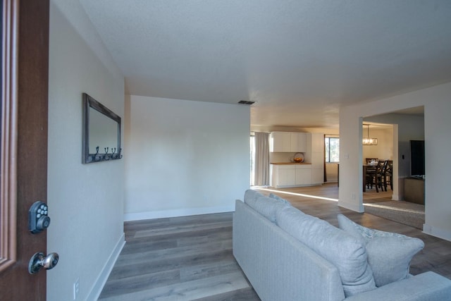 living area with baseboards, wood finished floors, and visible vents