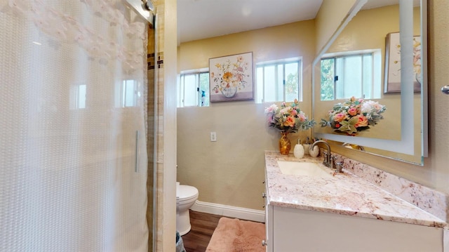bathroom with curtained shower, wood finished floors, toilet, vanity, and baseboards