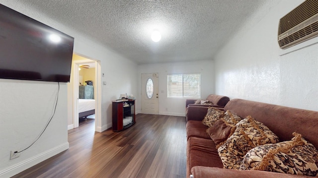living area featuring baseboards, dark wood-style flooring, a textured ceiling, and a wall unit AC