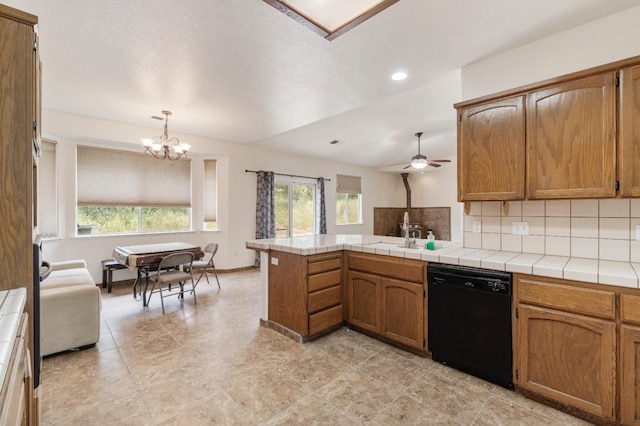 kitchen with a peninsula, tasteful backsplash, black dishwasher, and a healthy amount of sunlight