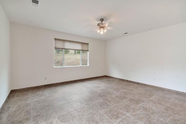 empty room featuring baseboards, a ceiling fan, and visible vents