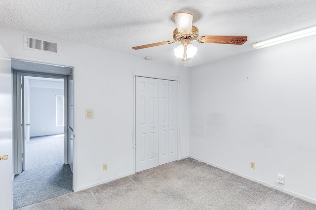 unfurnished bedroom featuring visible vents, carpet floors, a closet, baseboards, and a textured ceiling
