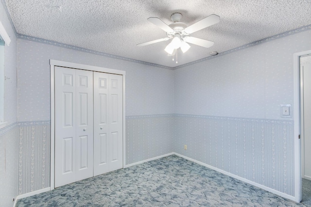 unfurnished bedroom with a textured ceiling, a closet, ceiling fan, ornamental molding, and carpet flooring