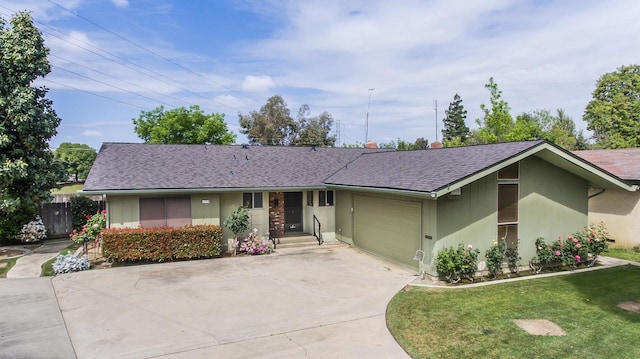 ranch-style house featuring a shingled roof, concrete driveway, a front yard, and a garage