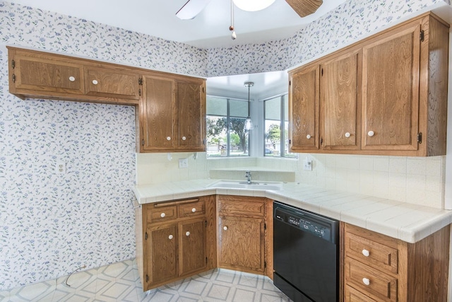 kitchen featuring black dishwasher, brown cabinetry, light floors, and a sink
