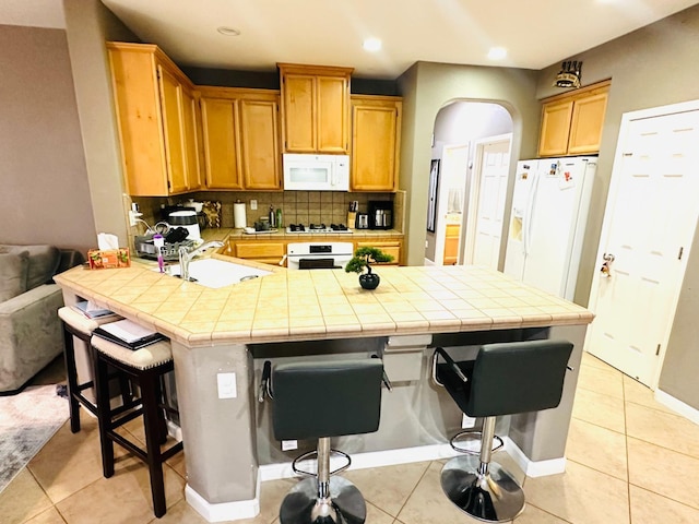 2148 S Villa Ave, Fresno, CA 93727 - kitchen featuring a peninsula, arched walkways, a sink, a kitchen bar, and white appliances