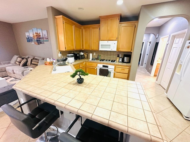 2148 S Villa Ave, Fresno, CA 93727 - kitchen featuring backsplash, tile countertops, white appliances, arched walkways, and light tile patterned flooring