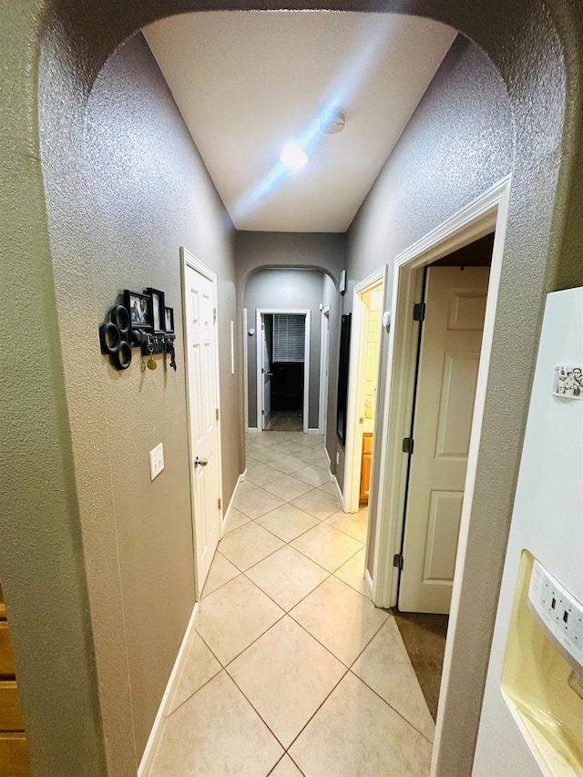 2148 S Villa Ave, Fresno, CA 93727 - hallway with arched walkways, a textured wall, baseboards, and light tile patterned floors