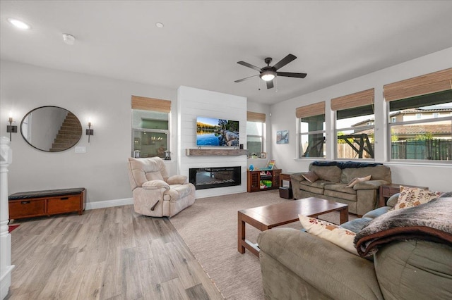 2653 Vermont Ave, Clovis, CA 93619 - living room featuring ceiling fan, light wood-style flooring, baseboards, and a glass covered fireplace