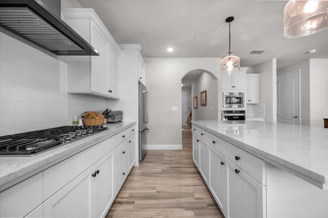 2653 Vermont Ave, Clovis, CA 93619 - kitchen featuring appliances with stainless steel finishes, wall chimney exhaust hood, arched walkways, light wood-style flooring, and white cabinets