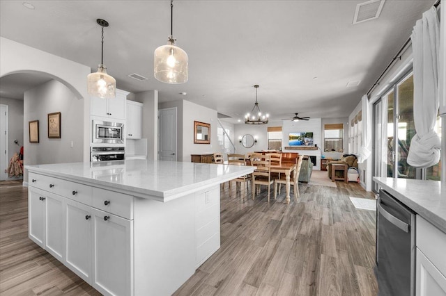 2653 Vermont Ave, Clovis, CA 93619 - kitchen featuring appliances with stainless steel finishes, arched walkways, light wood-style flooring, a ceiling fan, and white cabinetry