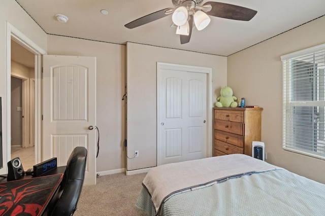bedroom featuring light colored carpet, baseboards, a ceiling fan, and a closet