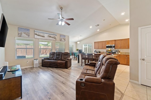 living room featuring high vaulted ceiling, a ceiling fan, light wood-type flooring, baseboards, and visible vents