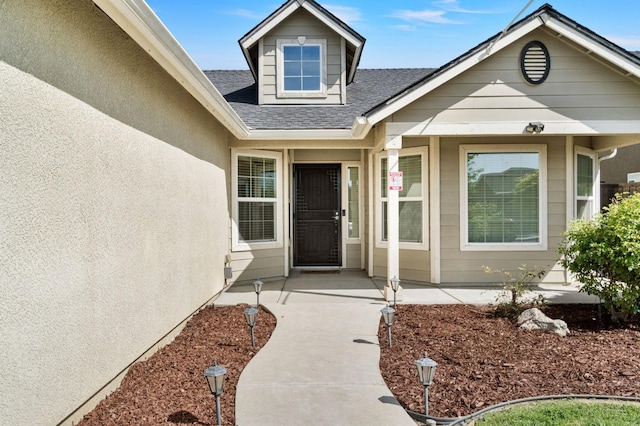 doorway to property with a shingled roof and stucco siding