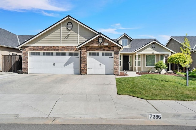craftsman inspired home with a garage, stone siding, a front yard, and concrete driveway