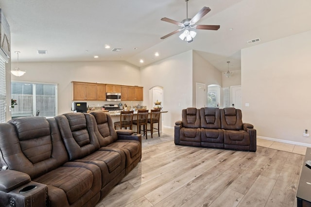 living room featuring arched walkways, a ceiling fan, light wood-style floors, and visible vents