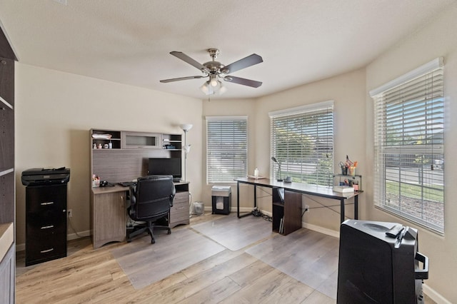 office with light wood-style floors, a ceiling fan, and baseboards