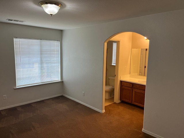 1836 Heidi Ave, Sanger, CA 93657 - unfurnished bedroom with connected bathroom, arched walkways, dark colored carpet, and visible vents